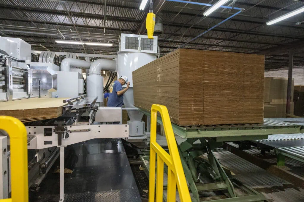 image of stacked boxes in the packaging facility with employee in background