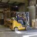 Man Driving Forklift Carrying Cardboard Bulk Stacks Of Cardboard Boxes