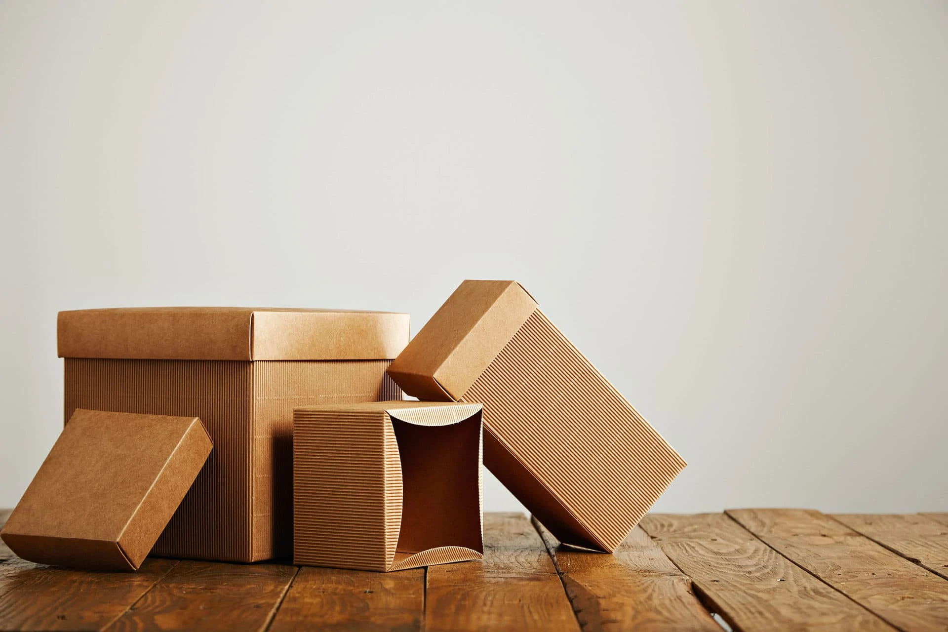 Set of three unlabeled similar craft cardboard boxes with covers beautifully arranged in a studio with white walls