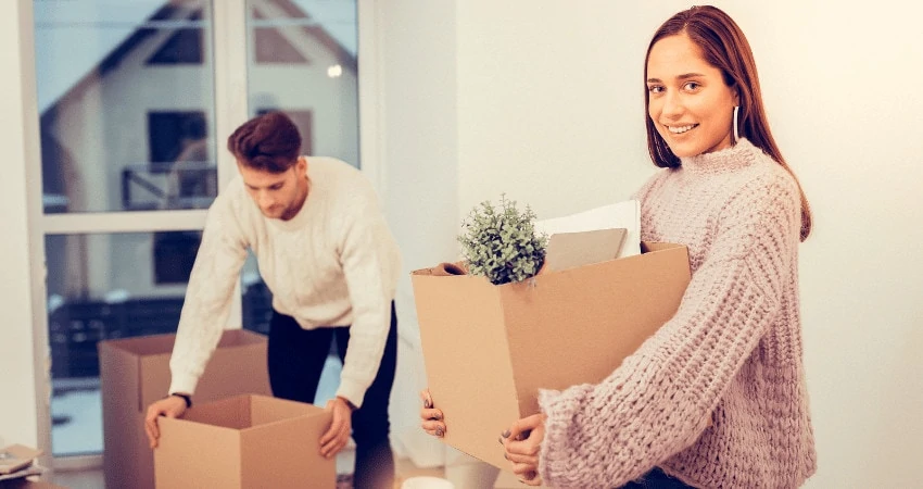 happy couple holding cardboard boxes moving