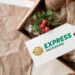 Gift Box Containing Natural Soap Bars, Greenery With Red Berries, And Twine, Accompanied By A Tag Featuring The 'Express Packaging' Logo In Green And Gold.