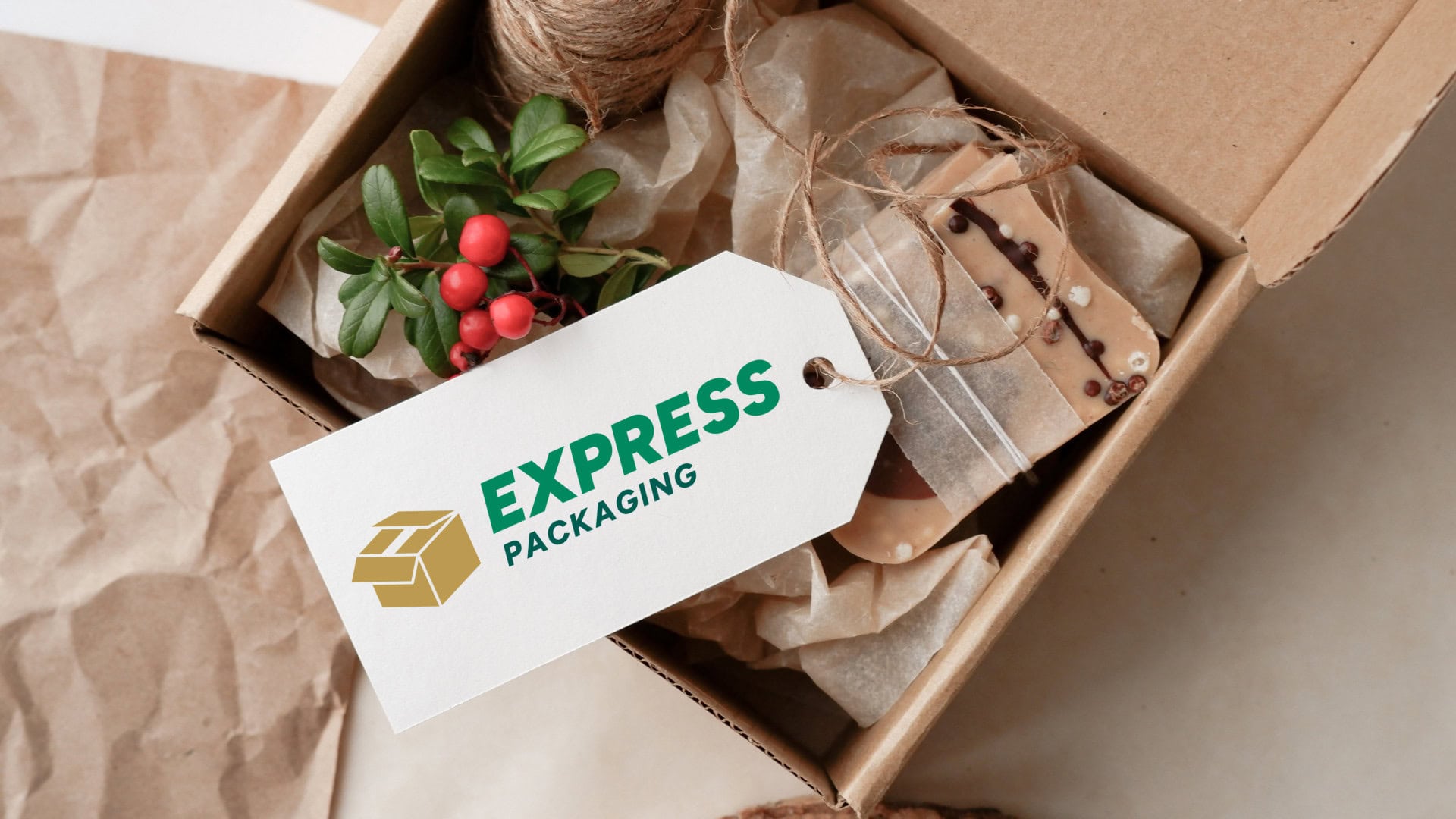 Gift box containing natural soap bars, greenery with red berries, and twine, accompanied by a tag featuring the 'Express Packaging' logo in green and gold.